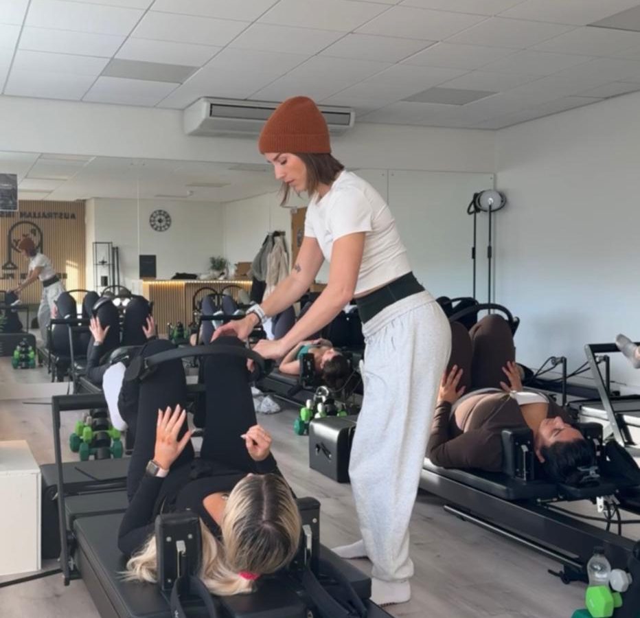 Instructor guiding clients through a reformer Pilates class at PXY