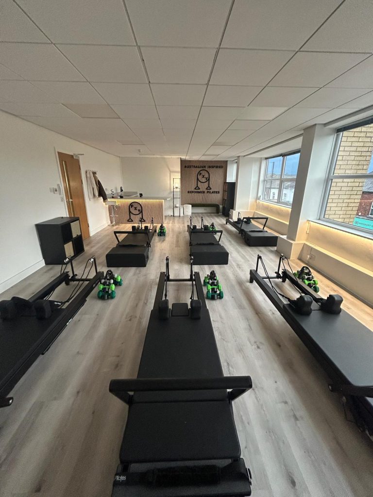 Reformer beds lined up inside the PXY Reformer Pilates studio in Didsbury