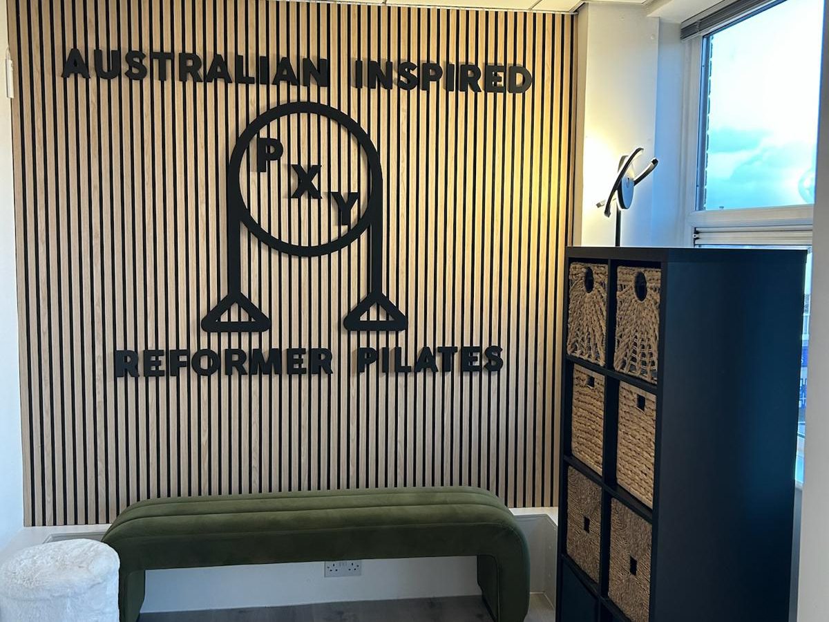 PXY Reformer Pilates logo wall and seating area inside the Didsbury studio