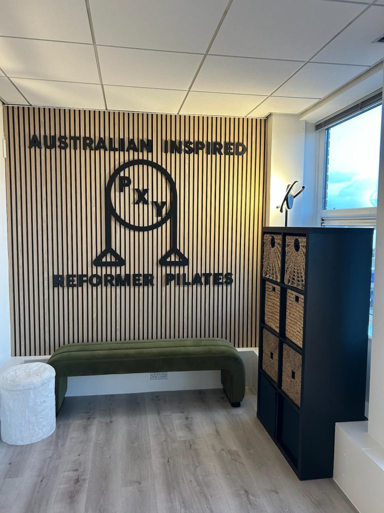 PXY Reformer Pilates logo wall and seating area inside the Didsbury studio