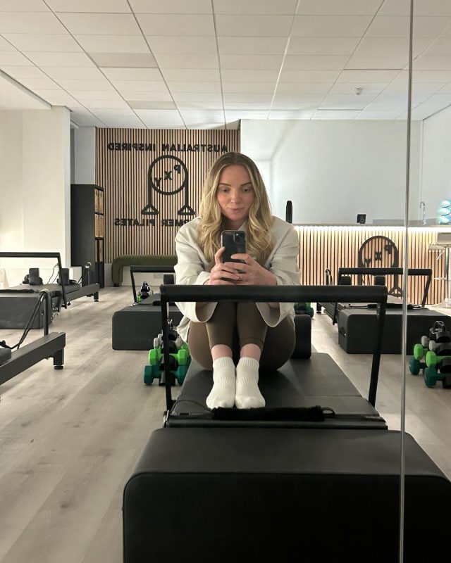 Olivia, founder of PXY Reformer Pilates, sitting on a reformer in the Didsbury studio